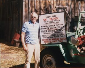 Mel Fletcher posing with a Snow Park Ski School sign, fall 1986.
