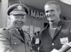 Bill Spencer in a CISM jacket shaking the hand of a military official, circa 1960s