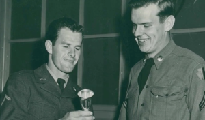 Dean Perkins and another soldier with a row of trophies during the ceremonies of the European Armed Forces Command skiing tournament, 1952.