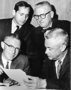 Wilby Durham (lower left), assistant general manager of the Deseret Newspaper, discusses plans to begin a community outreach program with Dev Jennings, Jack Wilson, and Stan Nelson. The program was aimed to teach both children and adults how to ski free of charge. The Deseret News Ski School started in late 1948 and ran every year for over half a century.