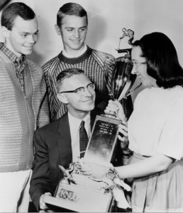 Wilby Durham holding the Knudsen Cup trophy, a Utah High School ski competition, surrounded by Criste Knudsen, Bill Latimer, and John Durham.